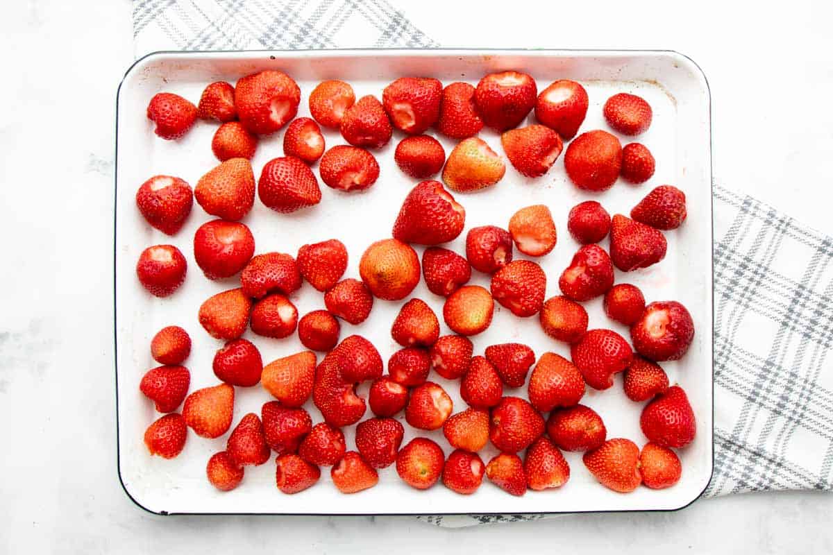 Overhead of fresh strawberries cleaned and hulled on a baking sheet.