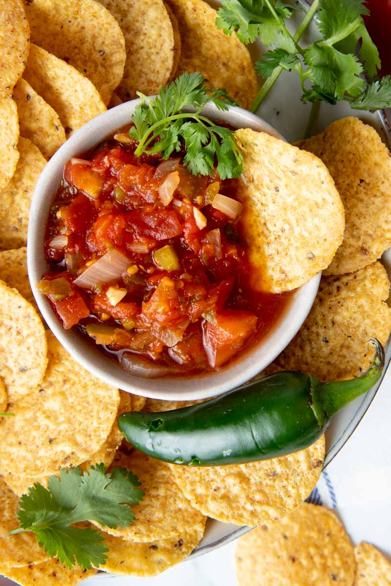 Overhead of canning salsa served on a platter surrounded by tortilla chips.