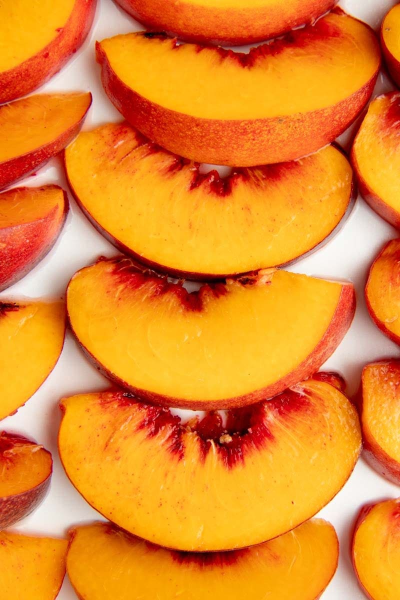 Close-up of a column of peach slices on a baking sheet.