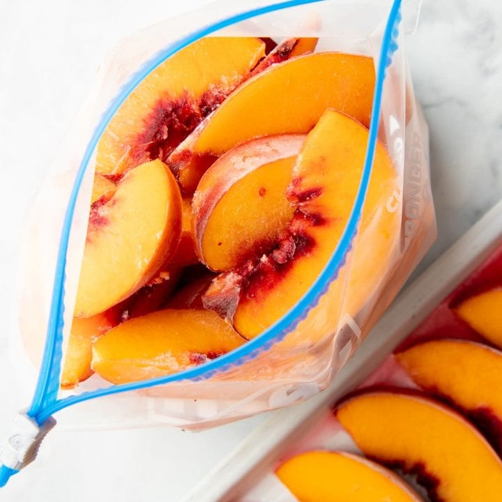 Overhead of open freezer bag filled with individually frozen peach slices.
