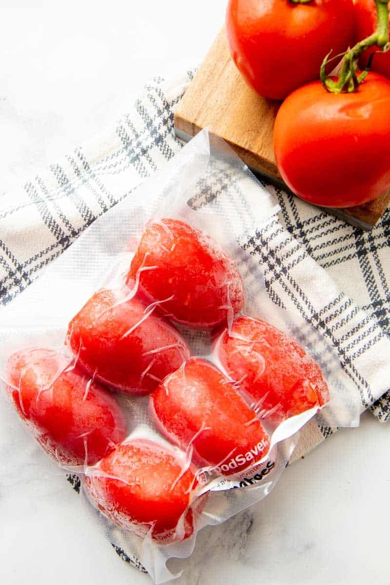 Six frozen roma tomatoes vacuum sealed and labeled.