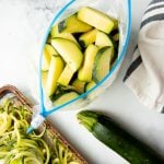 Overhead of open Hefty freezer bag filled with individually frozen slices of zucchini.