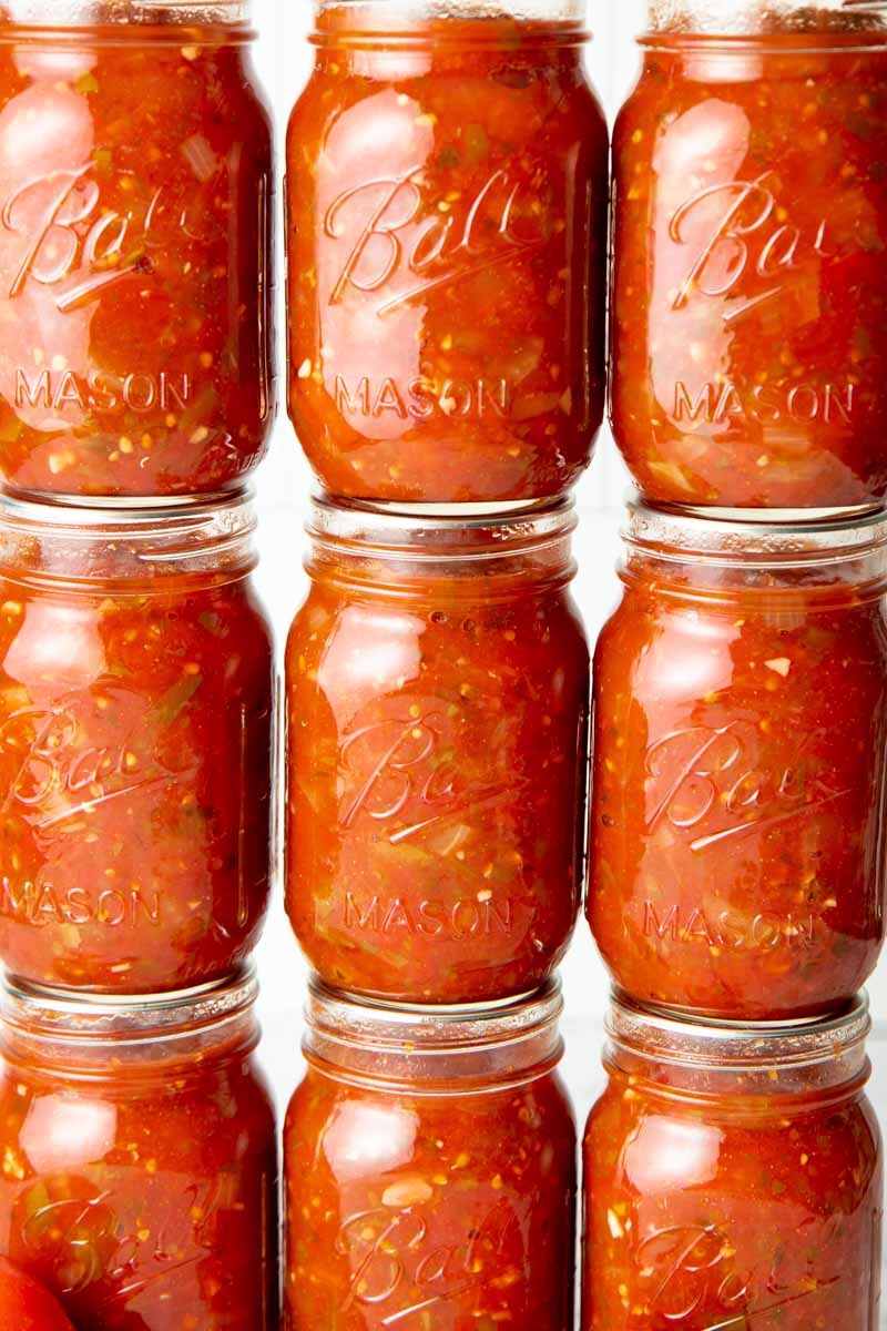 Close-up of canned salsa in mason jars stacked in a three-by-three grid.
