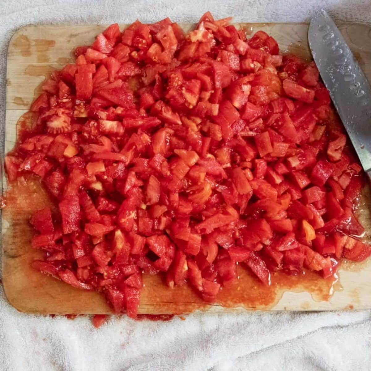Chopped tomatoes on a wooden cutting board with a large knife