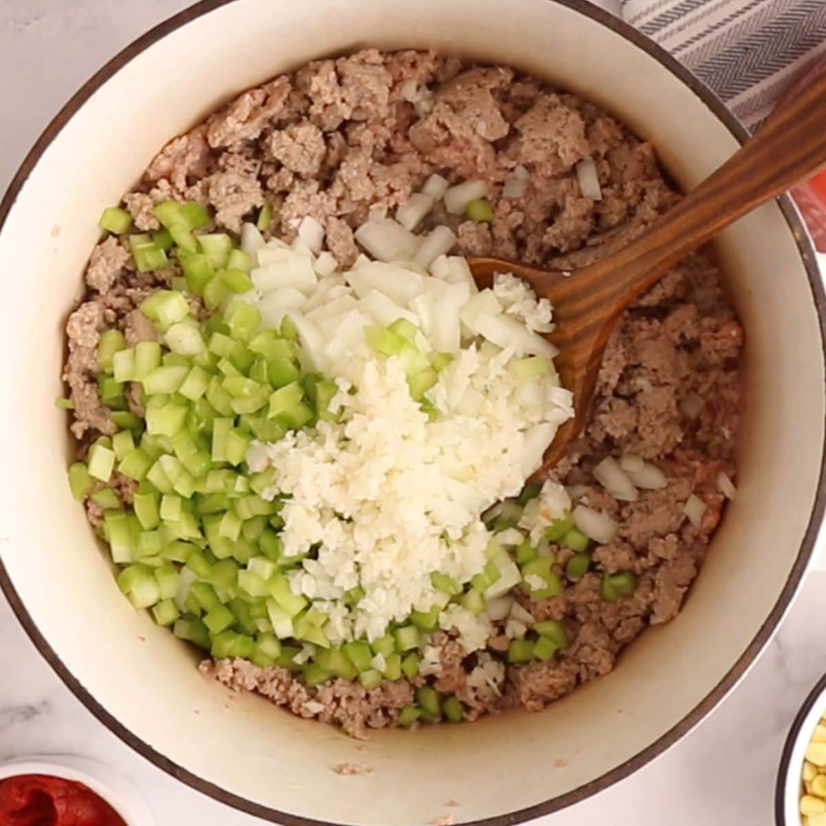 Celery, onion, garlic, and ground turkey browning in a white Dutch oven