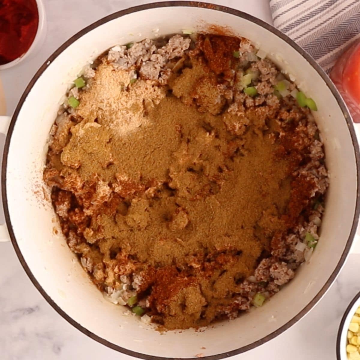 Chili seasonings and ground turkey in a white Dutch oven