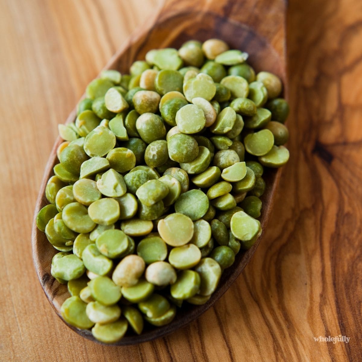 A spoonful of dried split peas on a cutting board