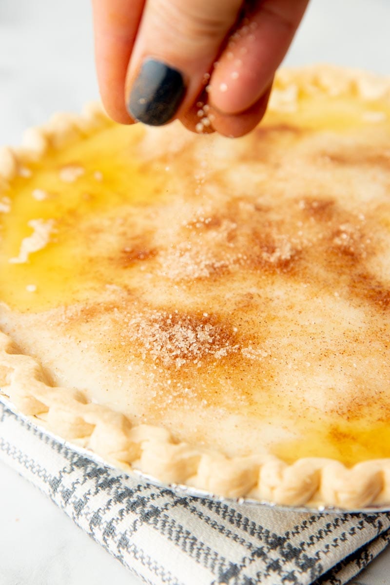 Close-up of hand sprinkling topping on hoosier pie.