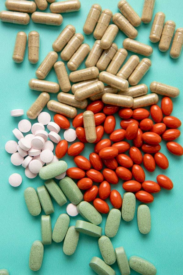 Overhead of four types of natural supplements in different shapes and colors piled together on a table.