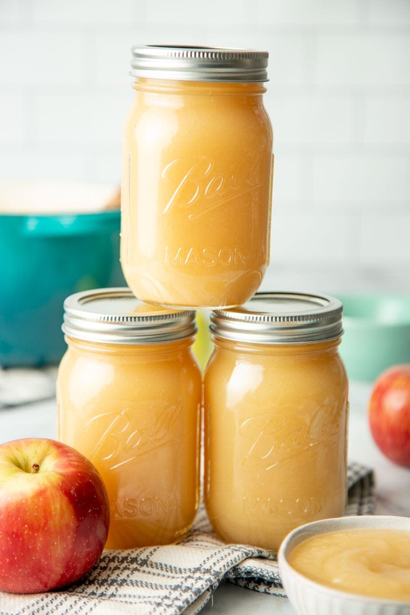 Close-up of three pint jars of homemade canned applesauce stacked in a pyramid.