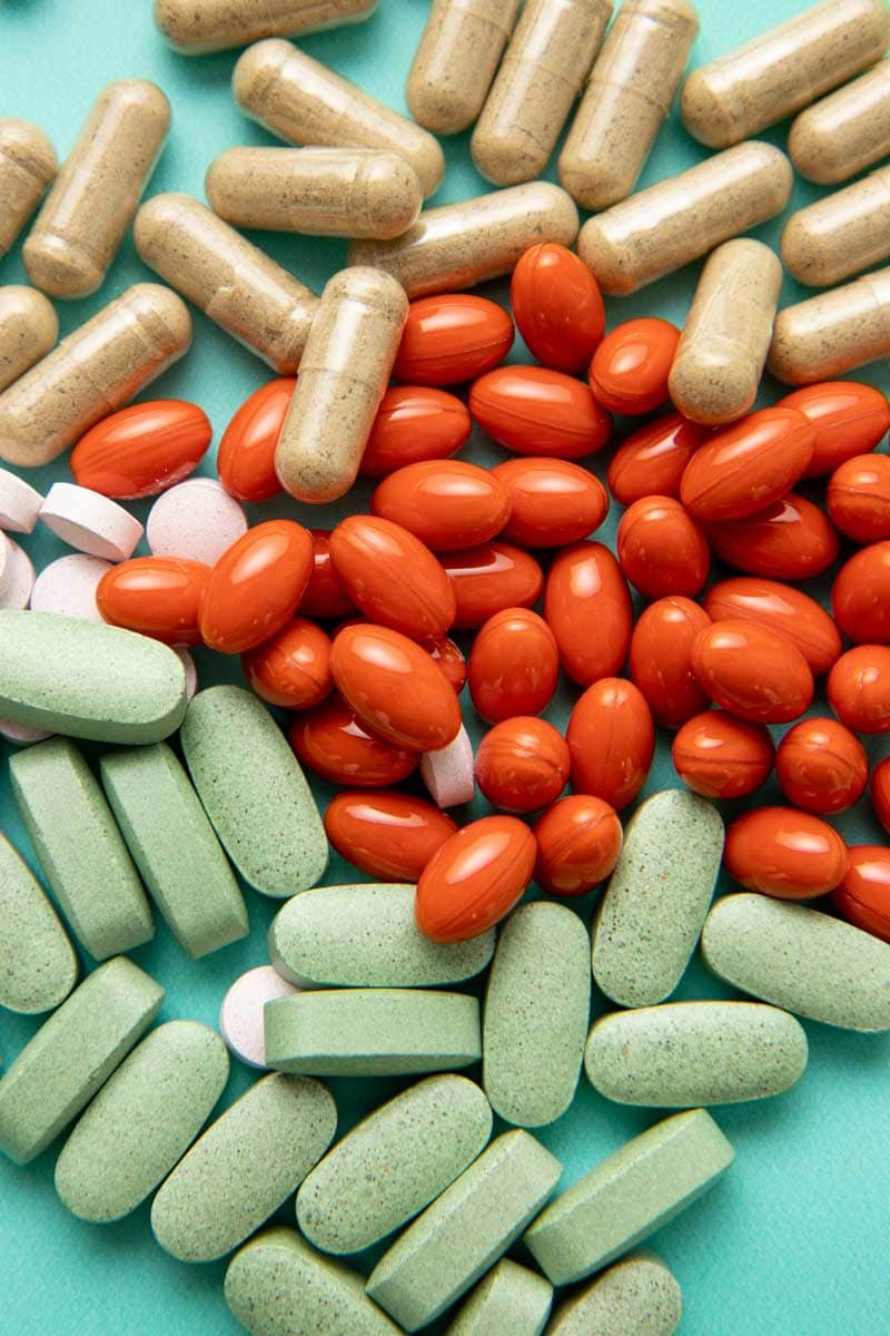 Close-up of four different varieties of herbal supplement pills and capsules.