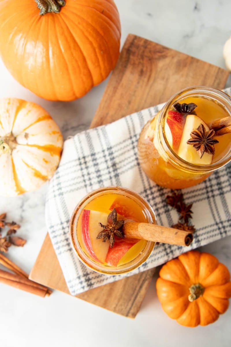 Overhead of two full glasses of pumpkin pie sangria garnished with cinnamon sticks and star anise pods.