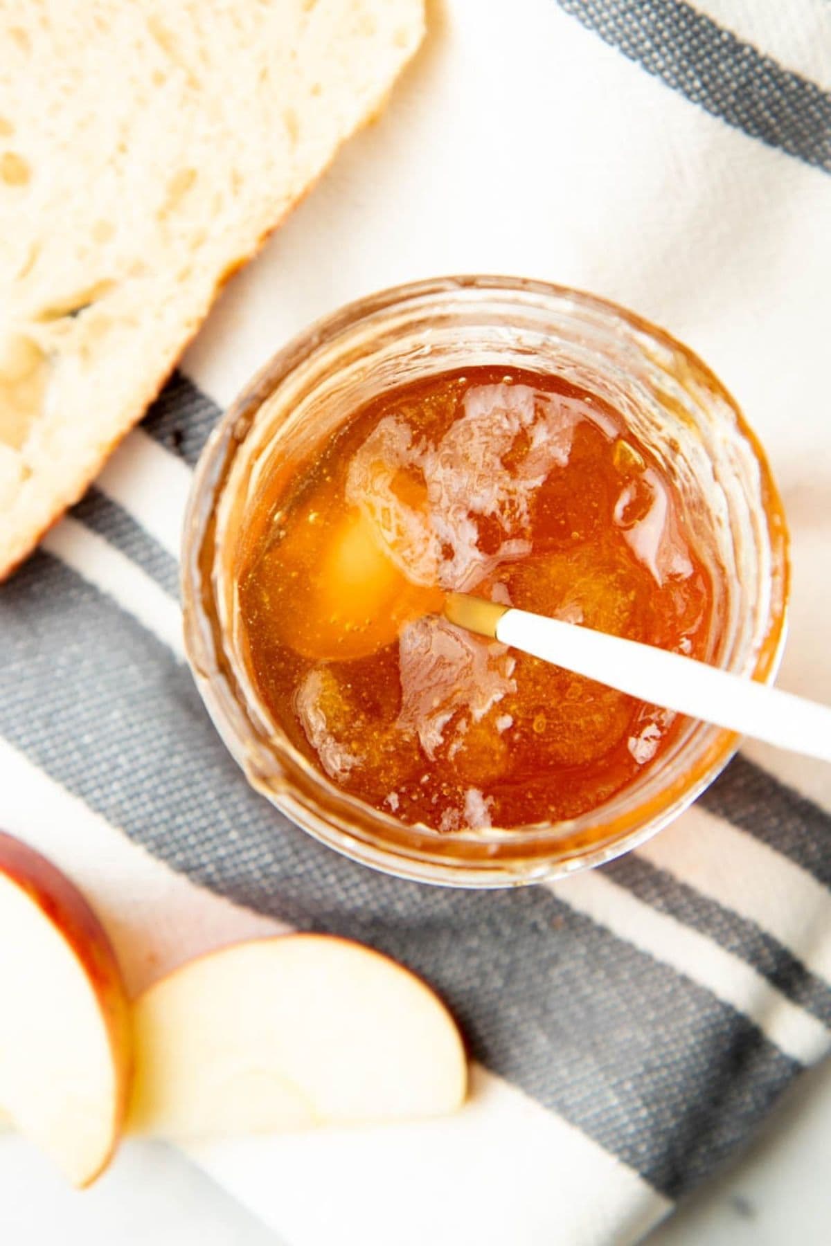 Open jar of apple jelly with a spoon in it