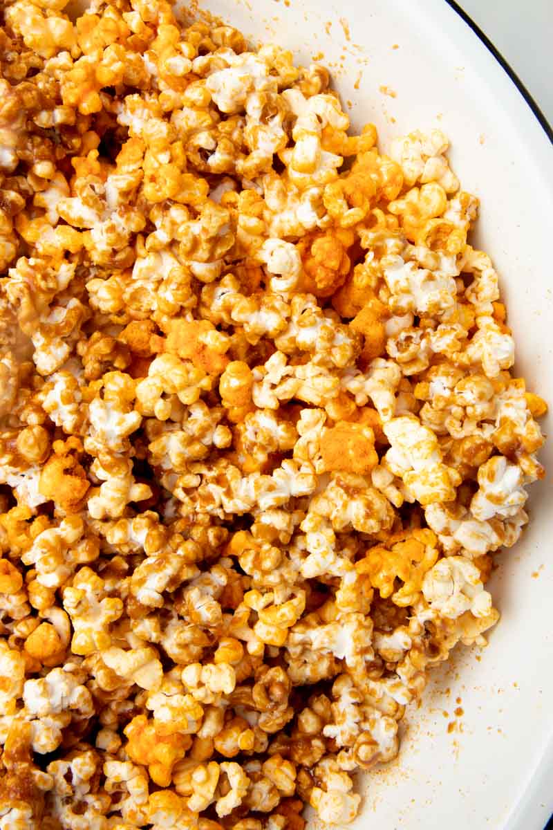 Homemade cheese and caramel popcorn mixed together in a large mixing bowl.