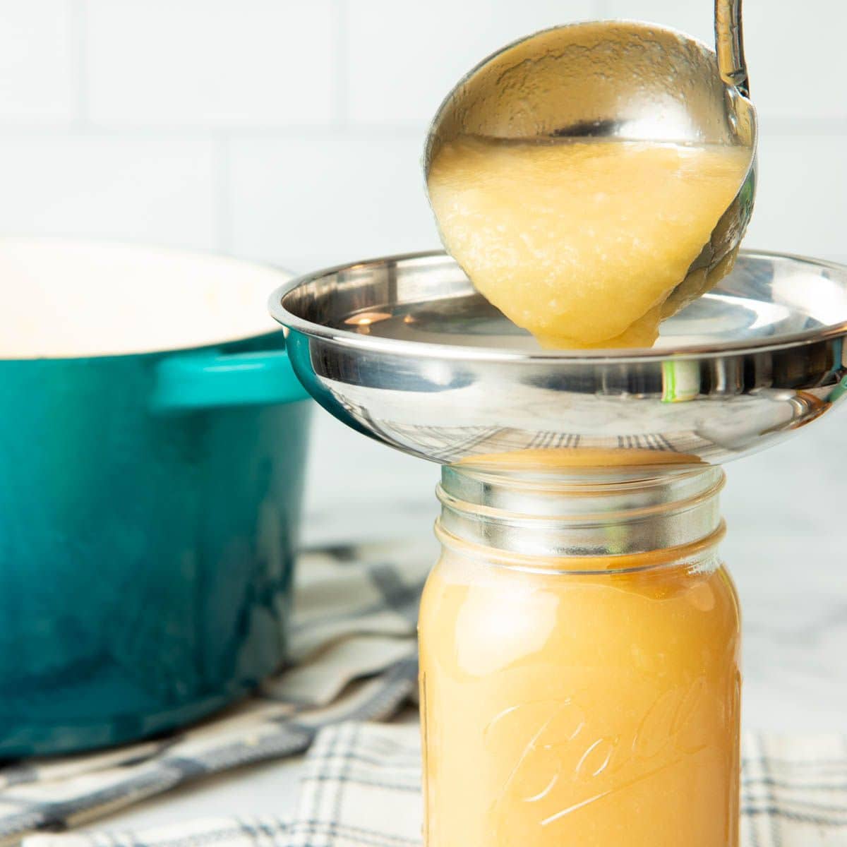 Ladling hot applesauce into a canning jar