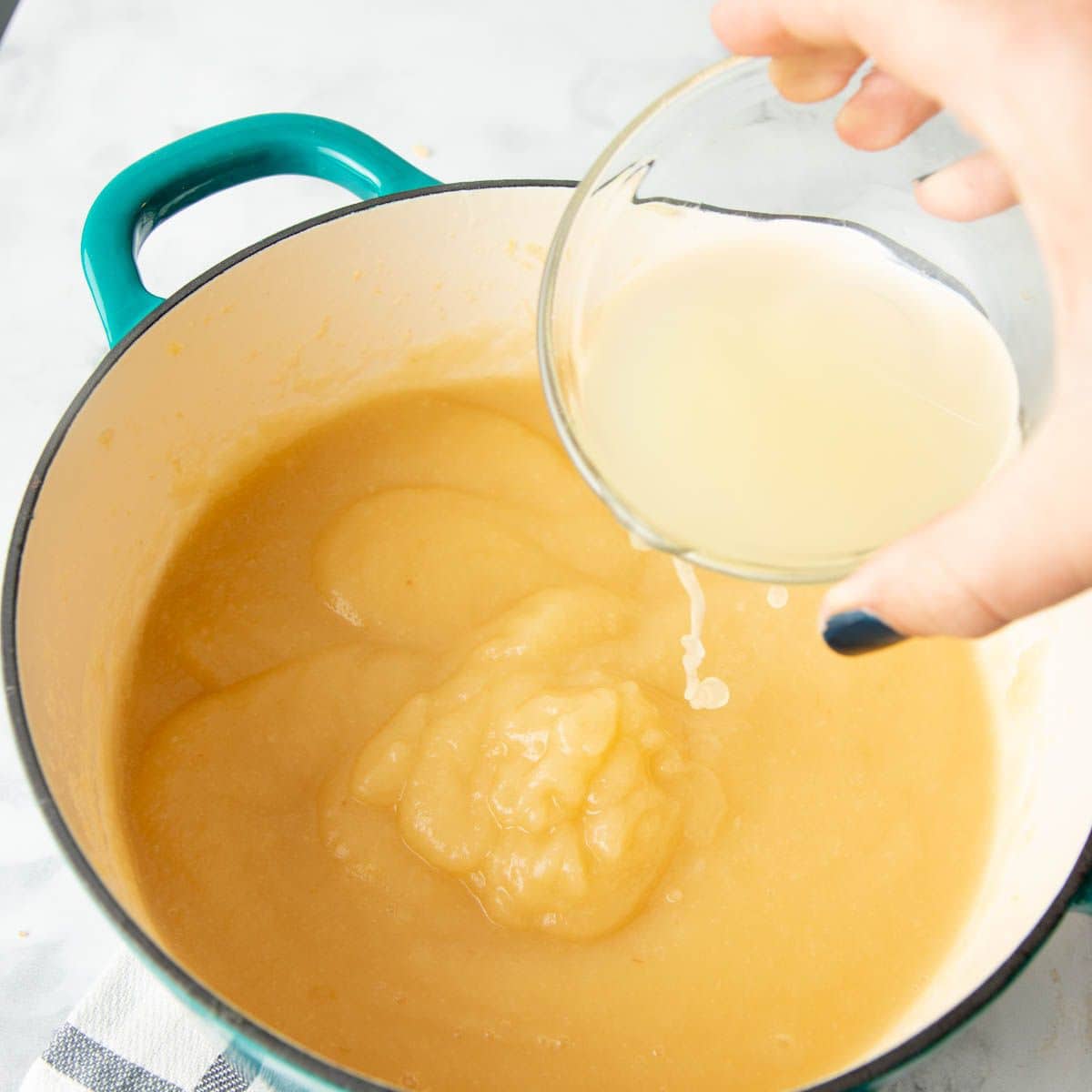 Pouring lemon juice into a pot of applesauce