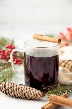 A mug of Christmas wassail sits with a cinnamon stick balanced across the rim.