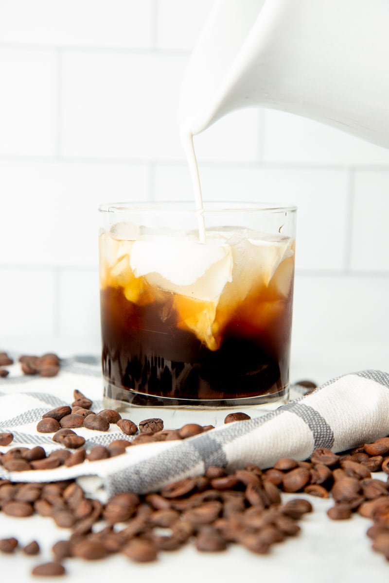Pouring cream into a rocks glass filled with homemade coffee liqueur, vodka, and ice.