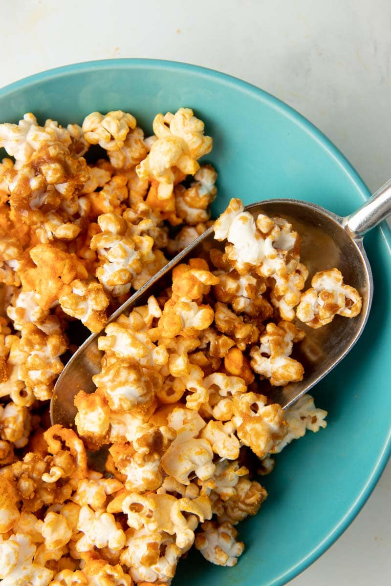 Scooping a single serving of chicago popcorn into a bowl.