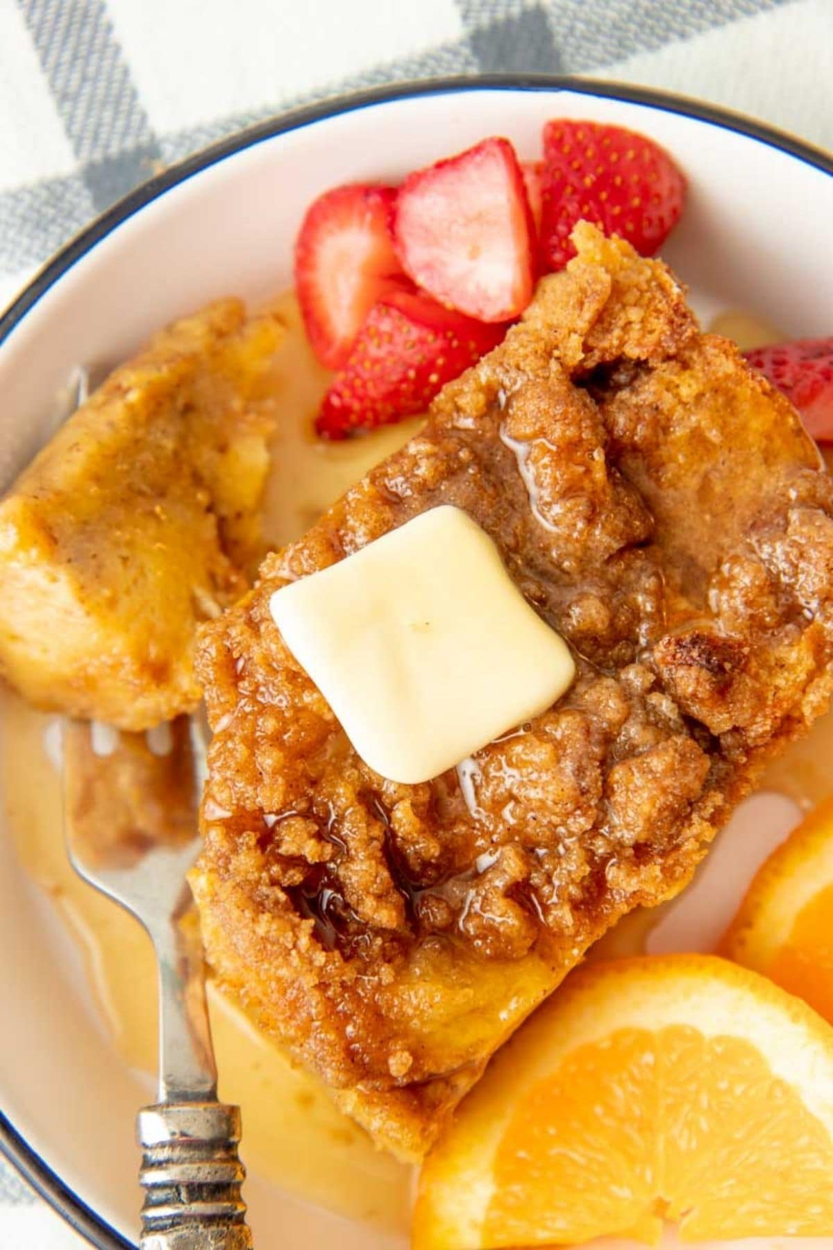 A pat of butter melts on a slice of French toast breakfast bake on a plate