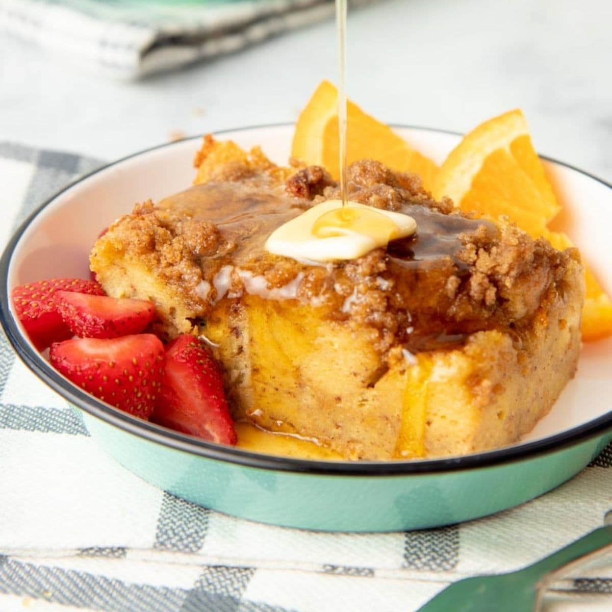 Pouring maple syrup onto a slice of French toast breakfast bake