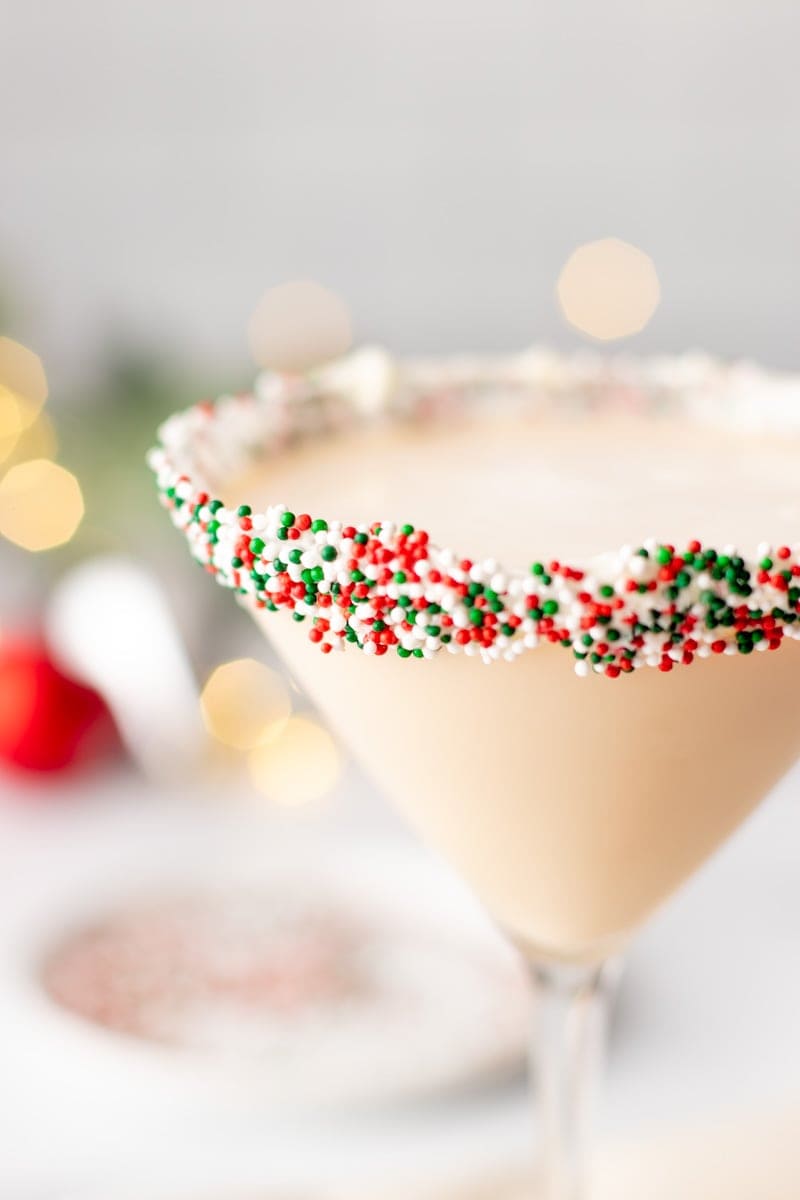 Close-up of Christmas sprinkles in red, green, and white around the rim of a holiday cocktail.