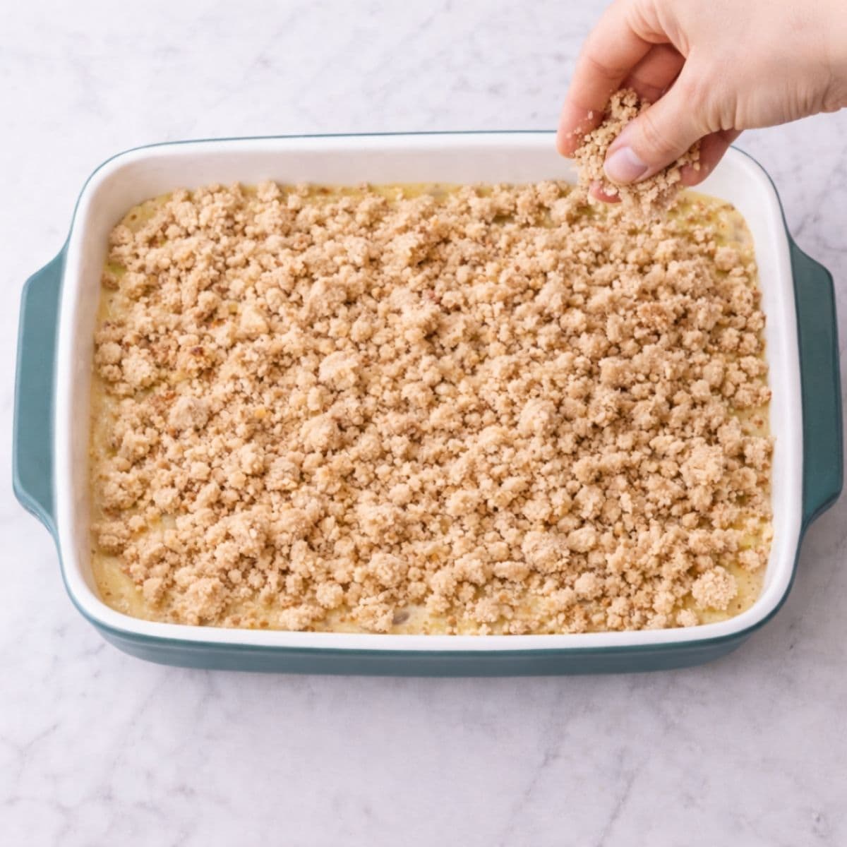 Sprinkling streusel onto French toast breakfast bake