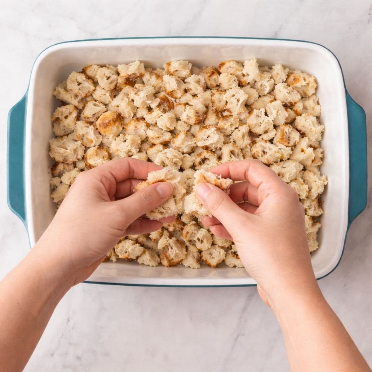 Tearing up bread into a casserole dish