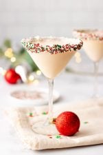A Christmas martini stands on a kitchen linen surrounded by holiday decor.