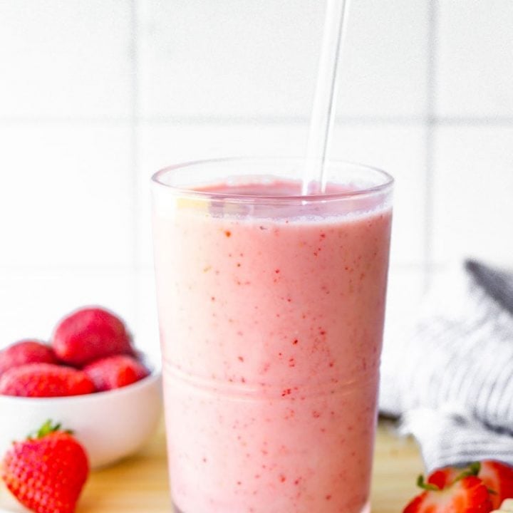 Strawberry banana smoothie served in a glass with a glass straw.