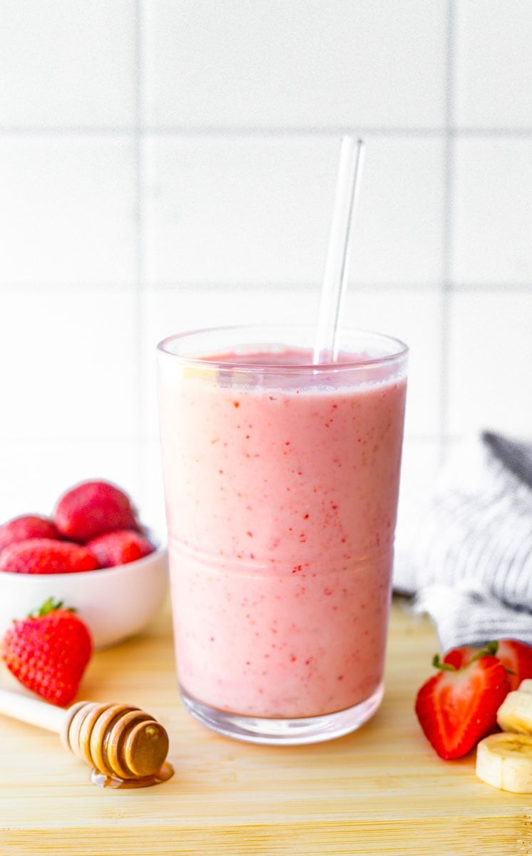 Strawberry banana smoothie served in a glass with a glass straw.