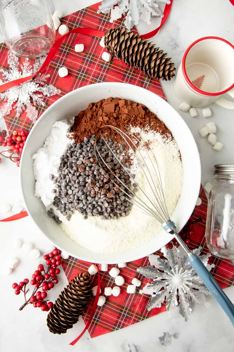 Overhead of ingredients for the best hot chocolate mix in a bowl with a whisk.