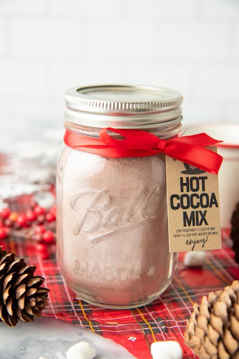 Close-up of a jar of hot chocolate mix packaged for gifting with a ribbon and label.