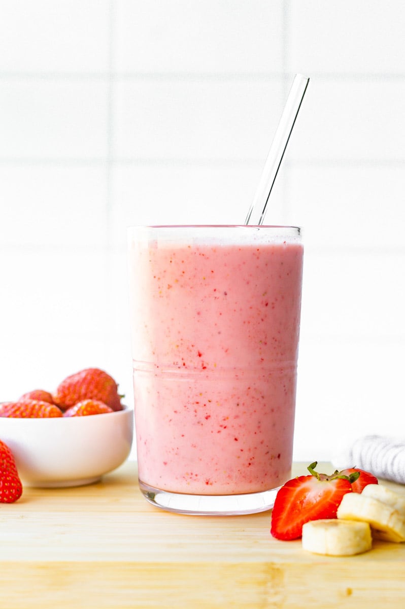 Easy strawberry banana smoothie in a glass with a glass straw.