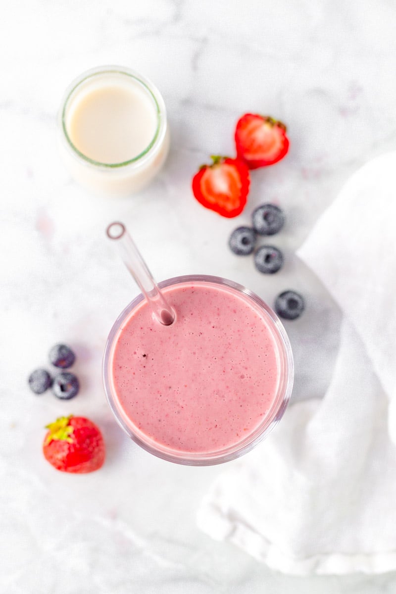 Overhead of finished smoothie with fresh berries and milk.