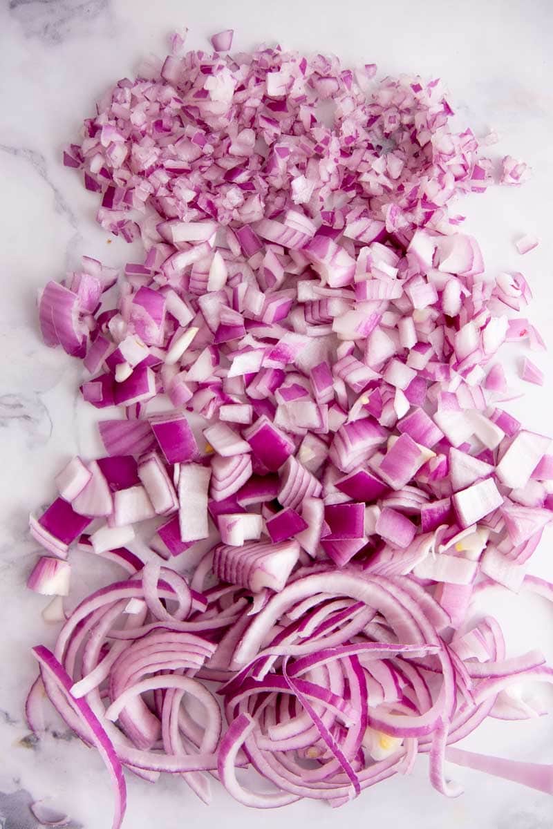 Overhead of long rows of minced, diced, chopped, and sliced red onions laid out from top to bottom.