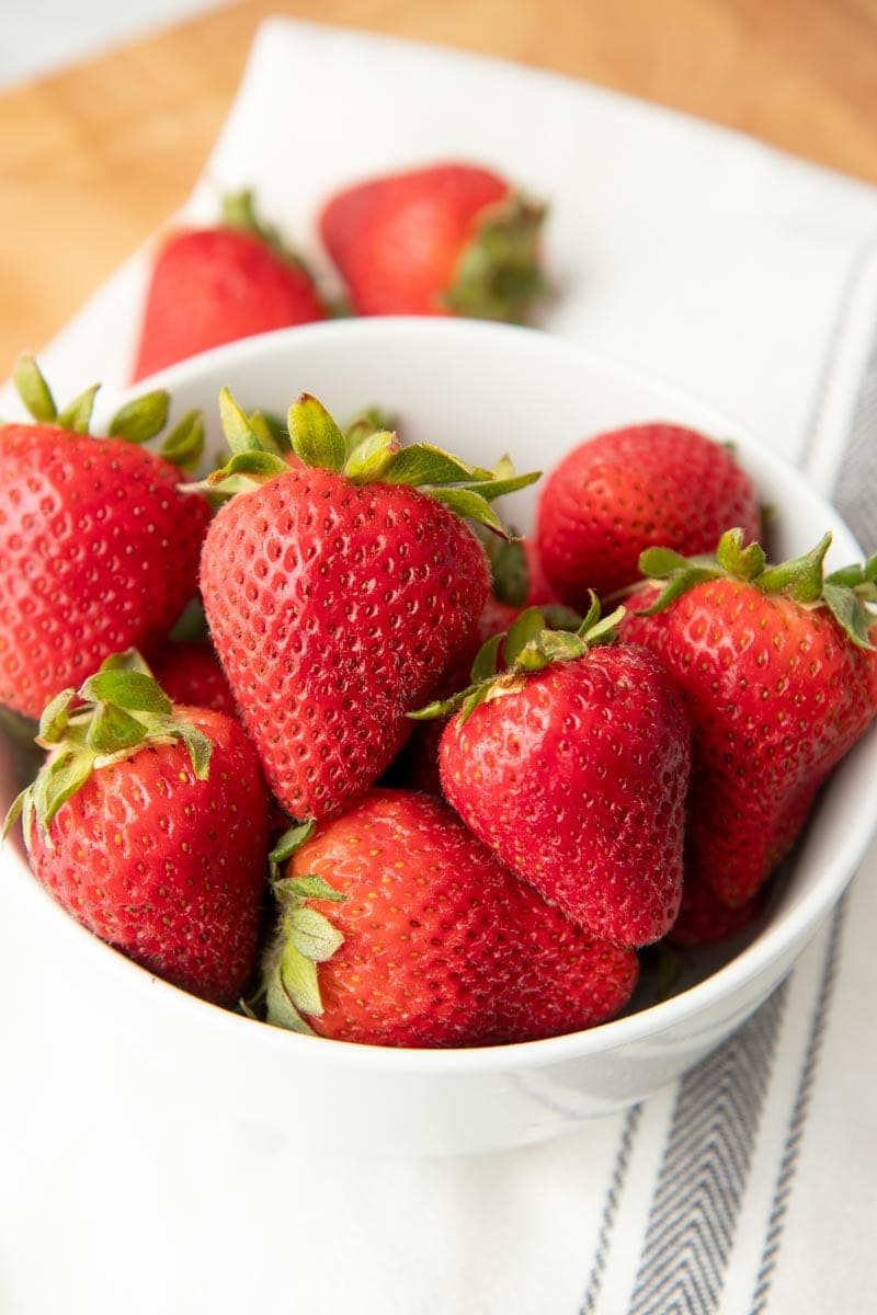 Fresh strawberries fill a white bowl