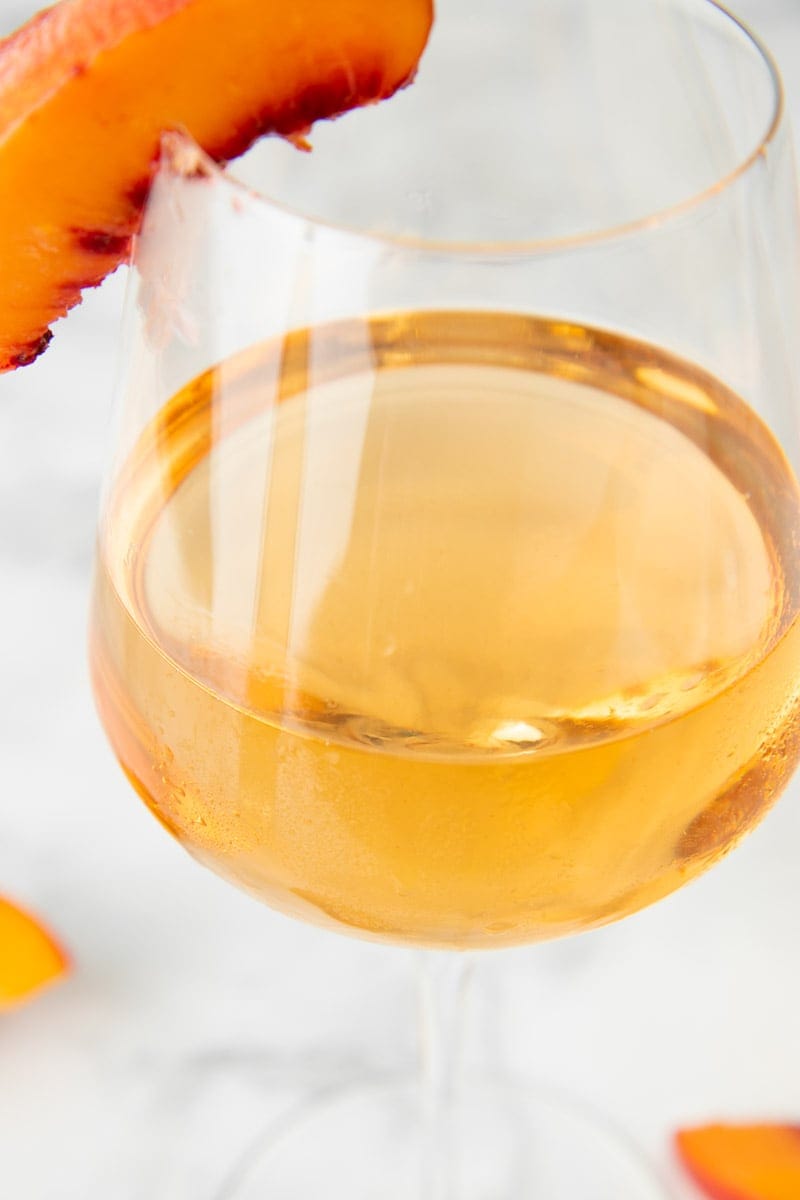 Golden peach wine close up in a stemmed wine glass.