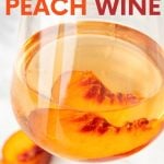 Close up of a glass of peach wine with a fresh peach slice in the glass. A text overlay reads, "How to Make Peach Wine."