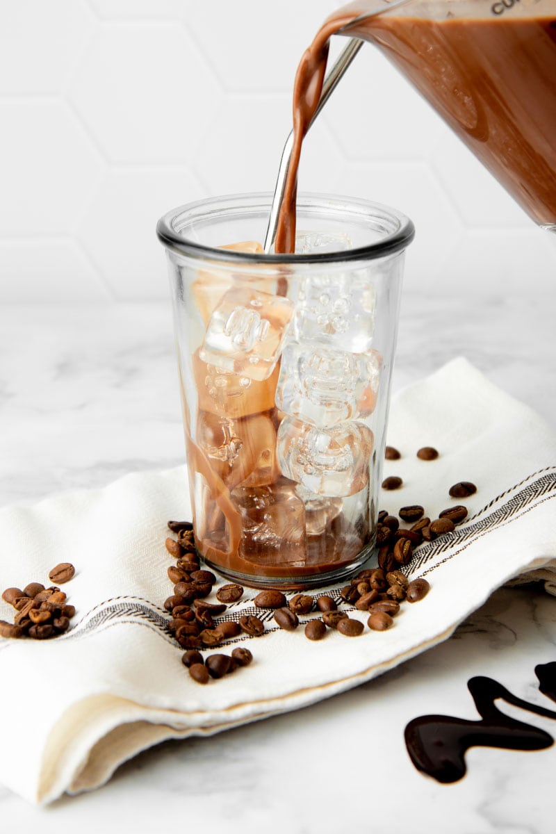 Pouring chilled mocha into a glass with ice.
