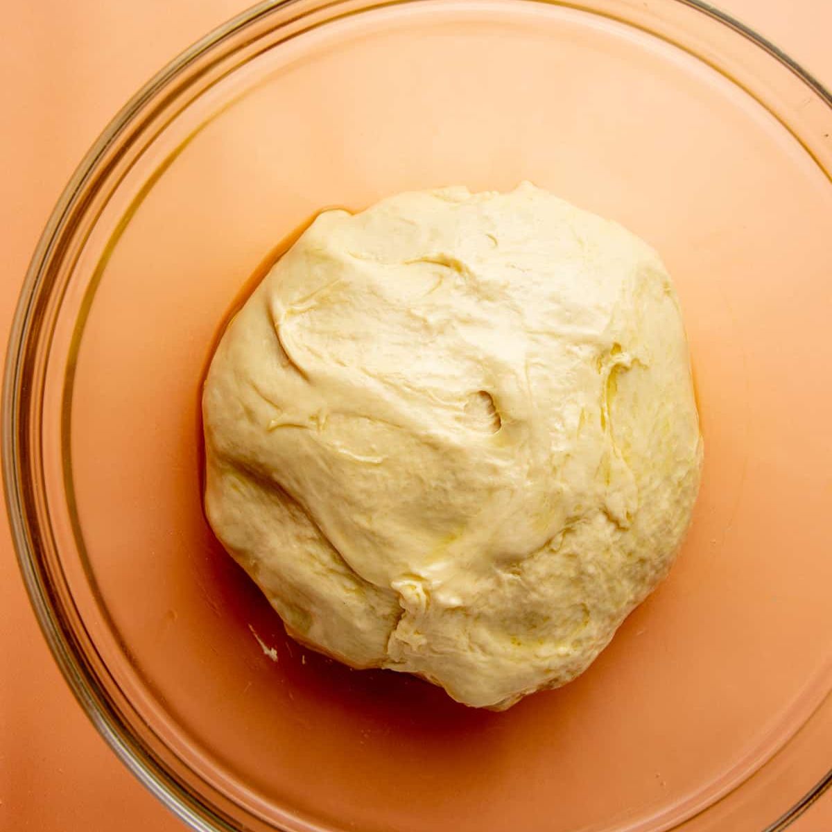 Kneaded sandwich bread dough transferred to a glass bowl before the first rise.