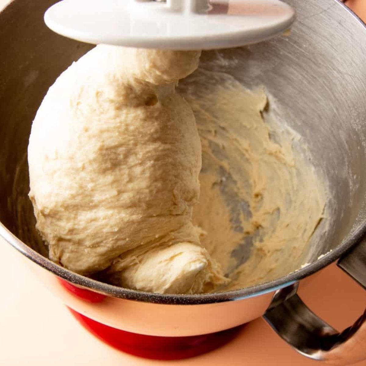 Sandwich bread dough kneading with a dough hook in a stand mixer.