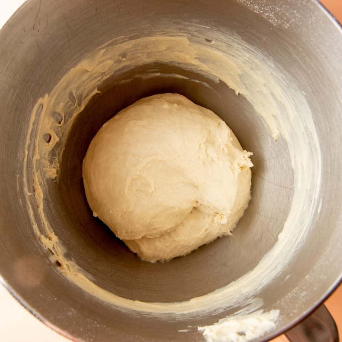 Smooth ball of sandwich bread dough in a stand mixer bowl after kneading.