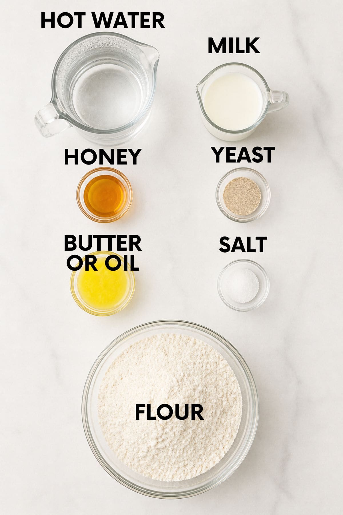 Ingredients for homemade sandwich bread in bowls on a white marble countertop