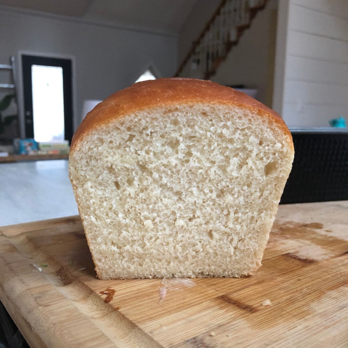 Sliced loaf of sandwich bread on a cutting board in a kitchen