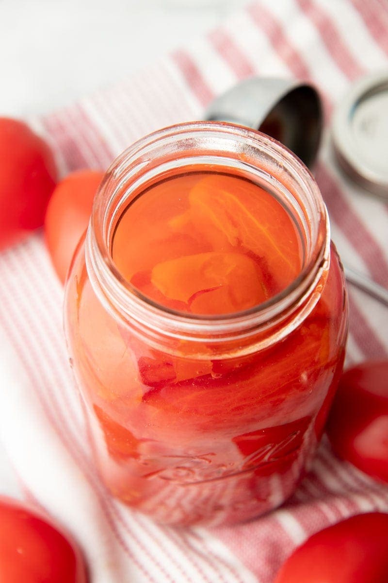 A look inside an open jar filled with tomatoes canned in their juices.