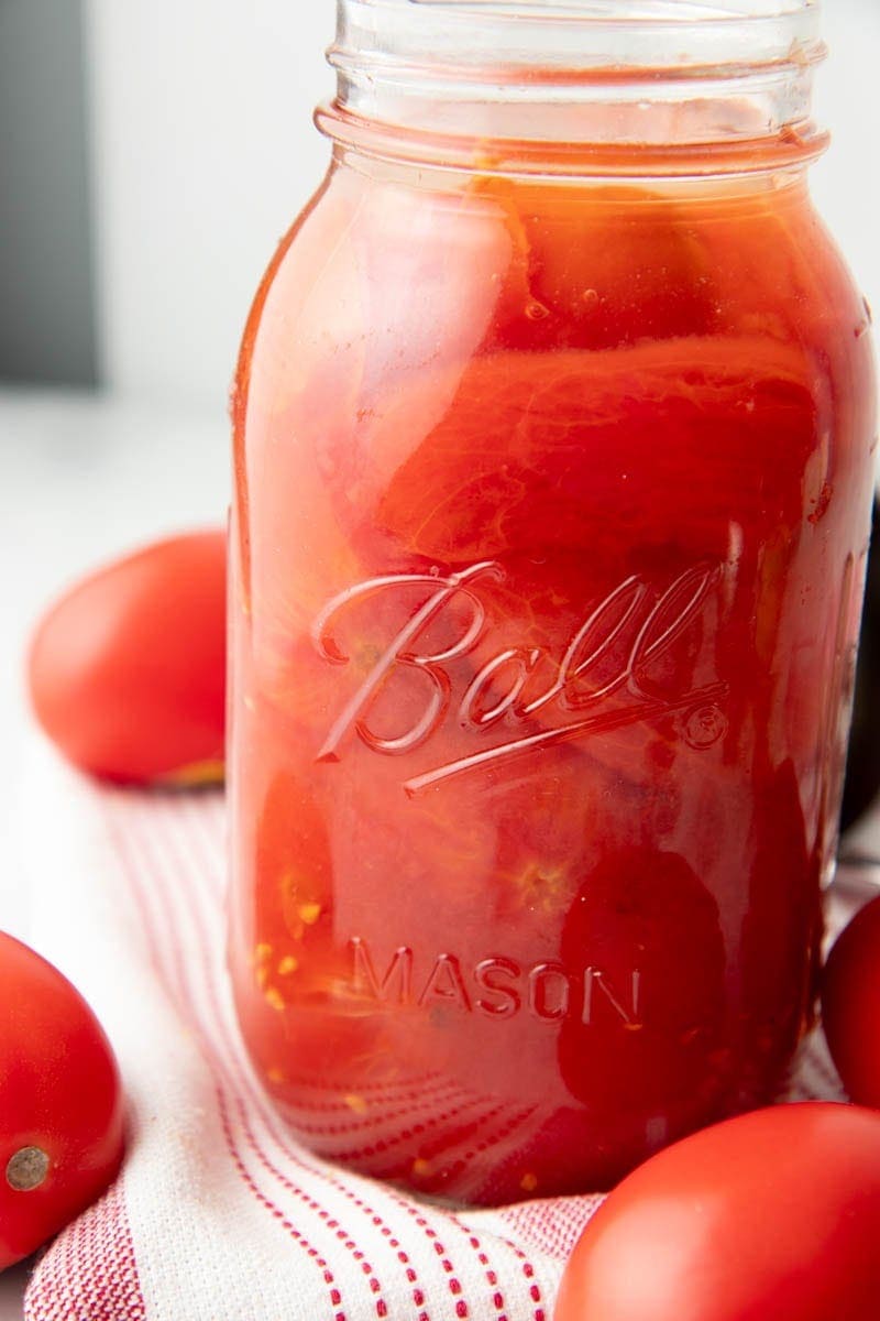 Close up of canned whole tomatoes in a jar.