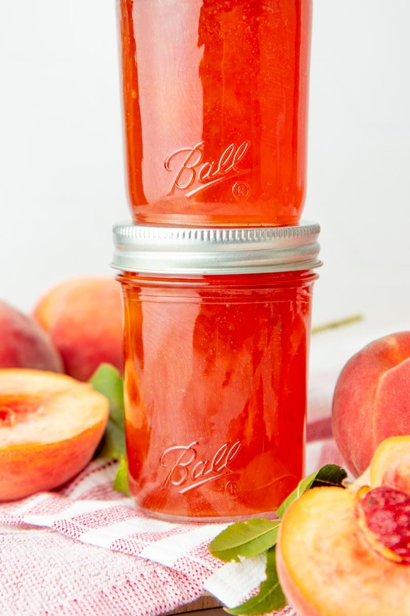 Two filled half pint canning jars are stacked on top of each other