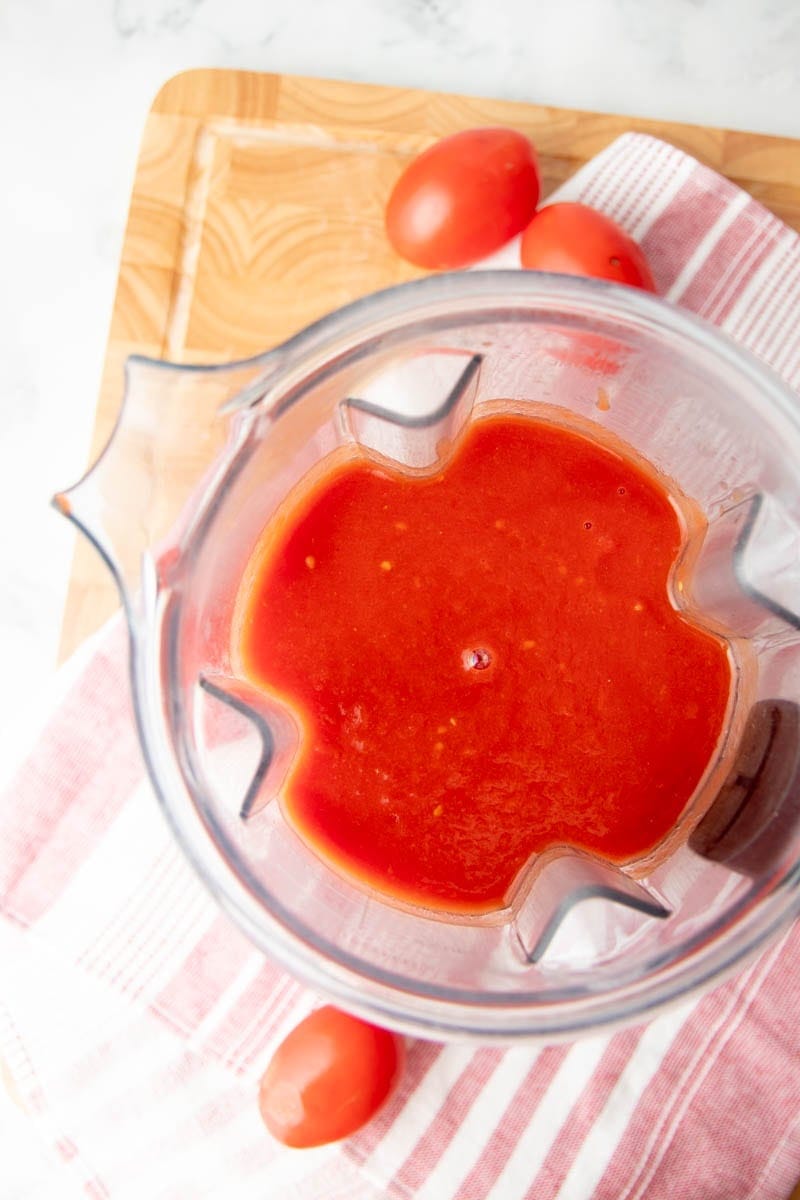 Overhead of smooth tomato puree in the carafe of a blender.