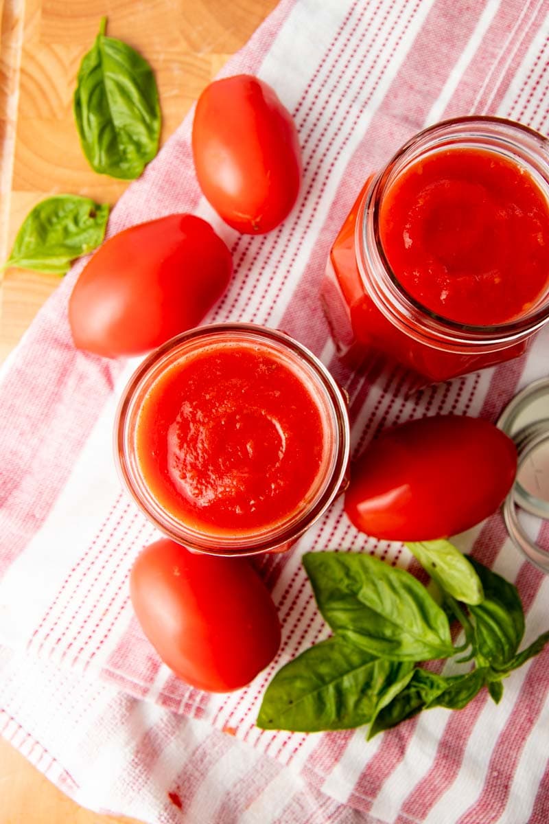 Overhead of two full jars of sauce with fresh ingredients around.